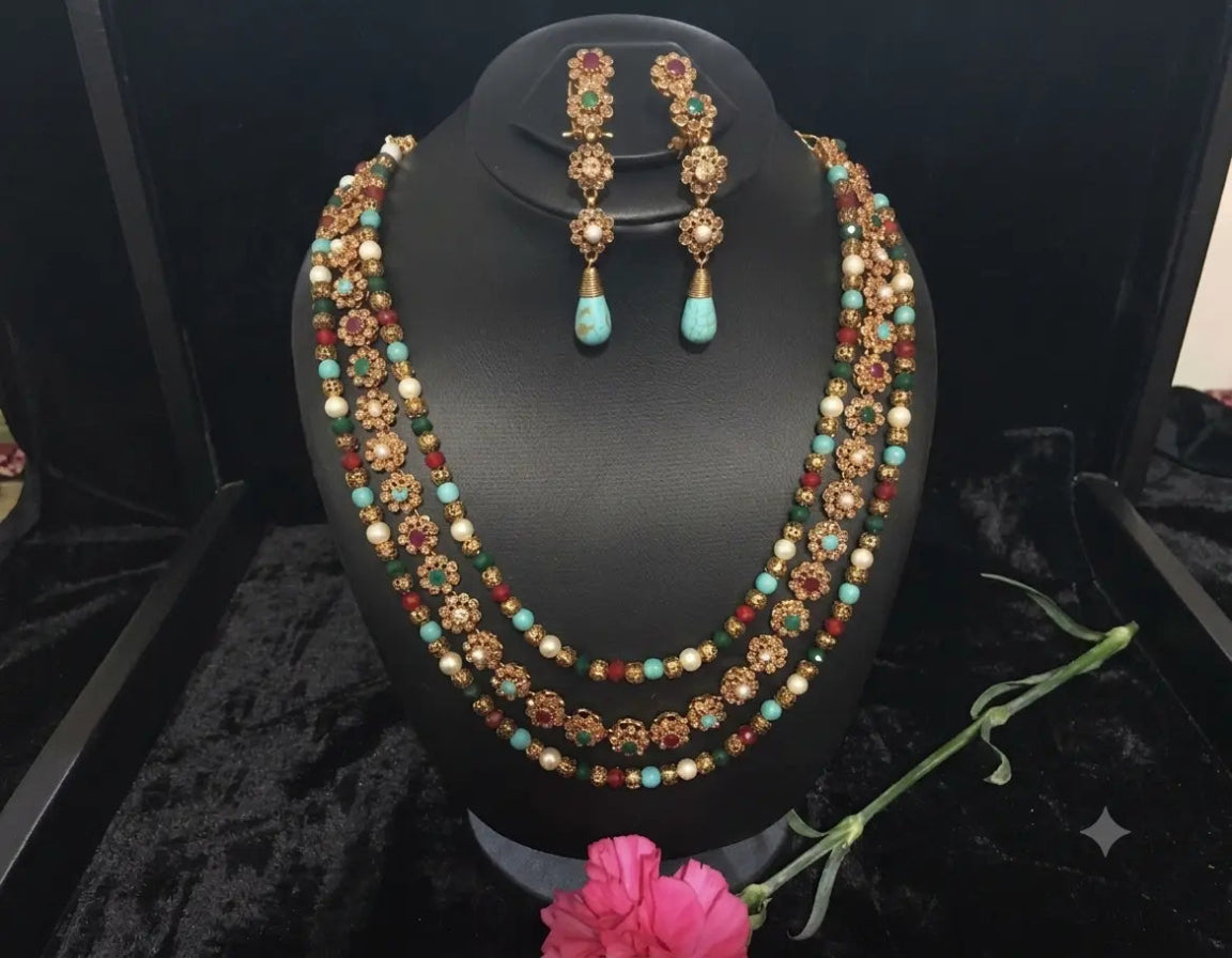 Jewelry set with necklace and earrings on a black stand with a pink flower.