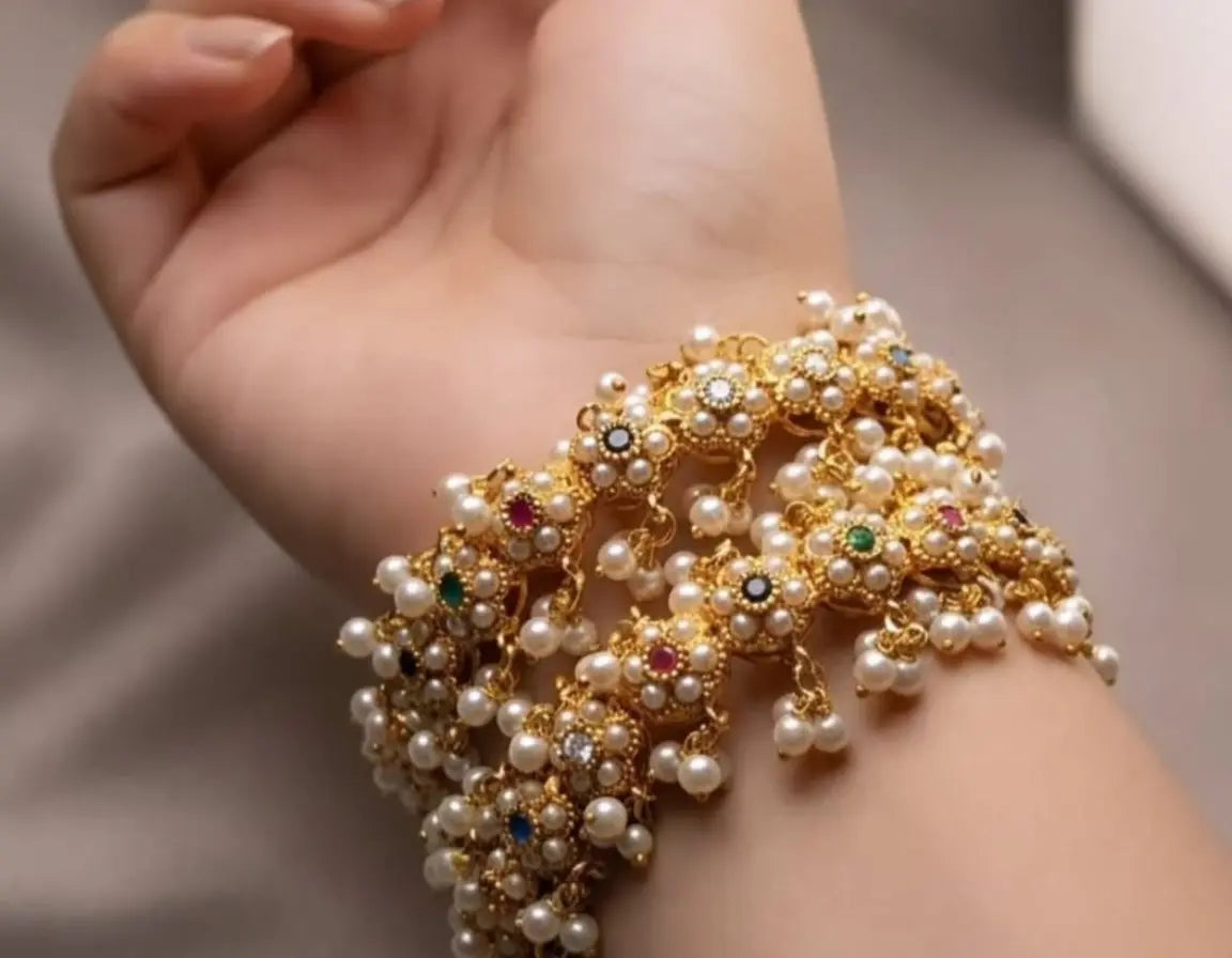 Delicate pearl and gemstone bracelet on a hand against a neutral background