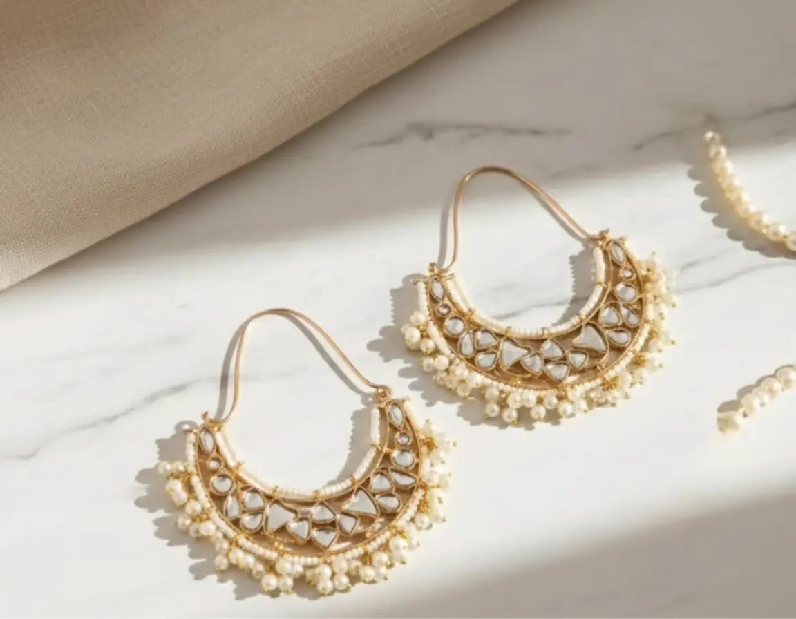 Gold and pearl earrings on a marble surface