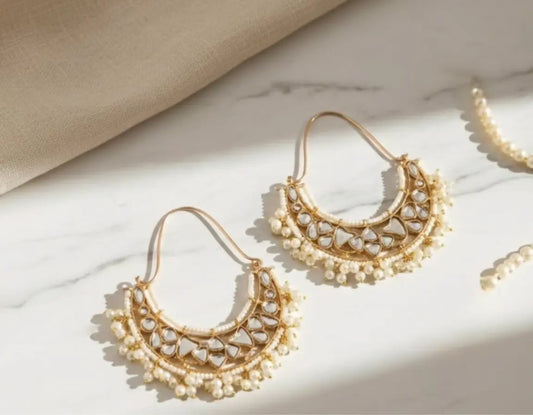 Gold and pearl earrings on a marble surface